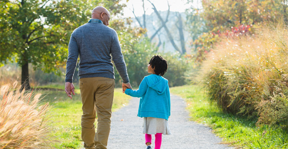 Grandfather walking in the park with granddaughter