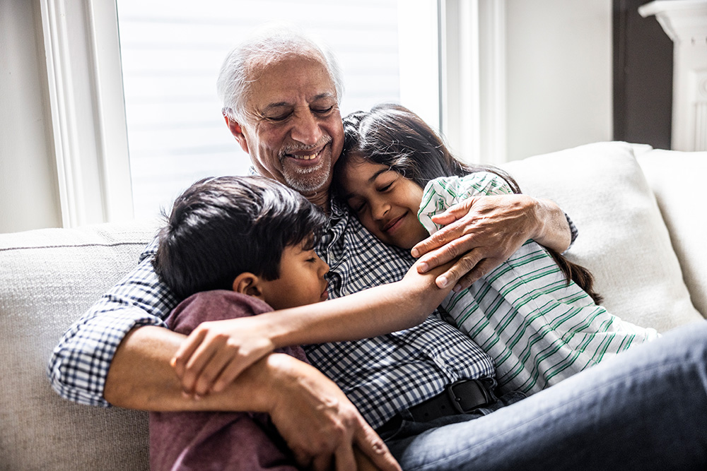 grandfather hugging two kids sitting on a couch